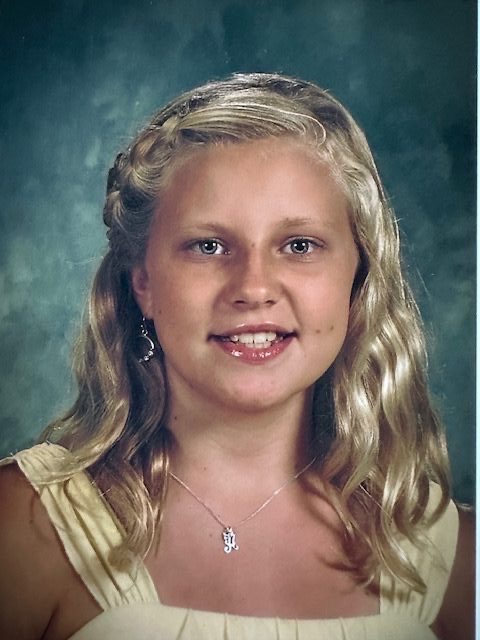 Abbi as a teen — school portrait, blonde hair, kind eyes