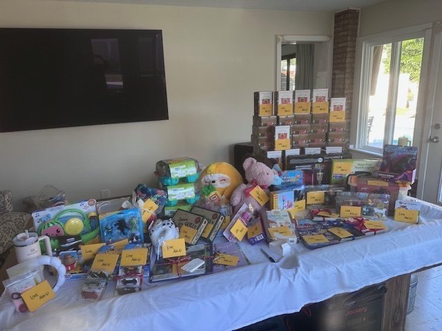 Massive table of donated toys, books, and bags ready for delivery