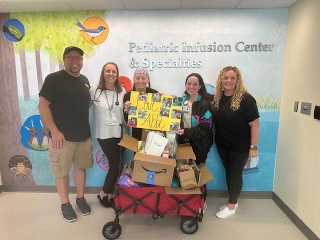 Family with hospital staff at the Pediatric Infusion Center holding Love Abbi sign