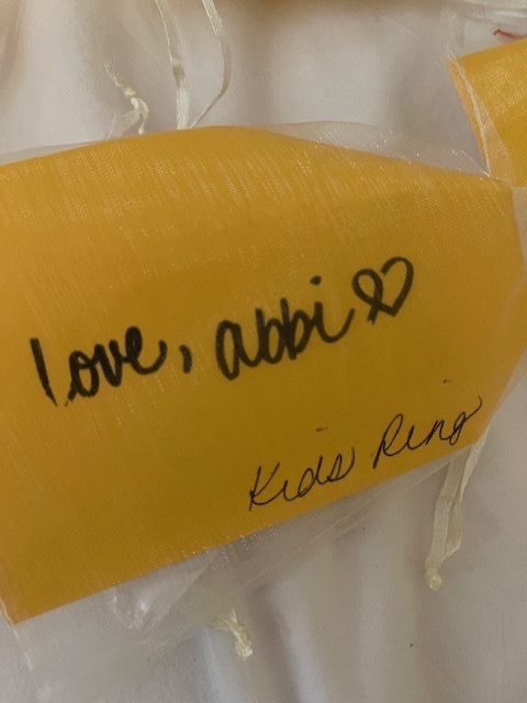 Handwritten yellow gift tag reading 'love, abbi' with heart