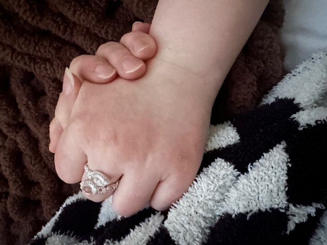 Two hands held together — a tender moment of love between Abbi and her mother